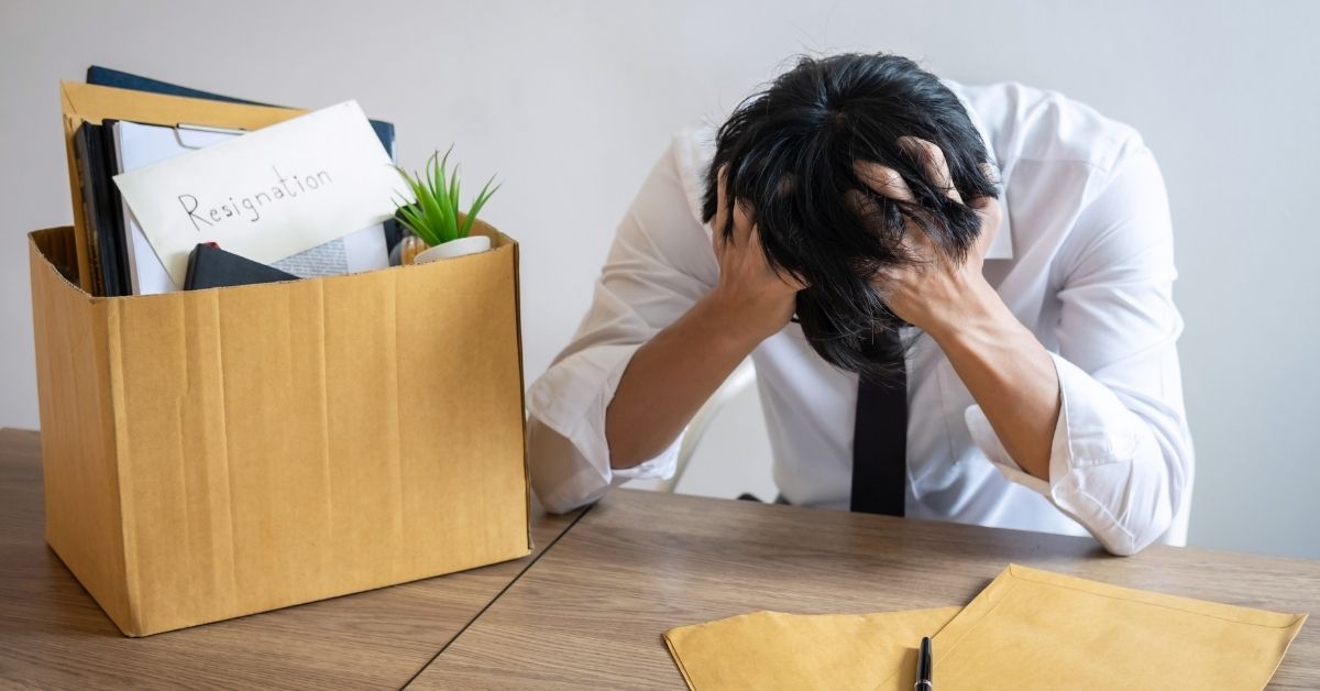 A stressed employee sitting at an office desk looking at a resignation letter, symbolizing forced resignation or constructive dismissal in an employment law context.